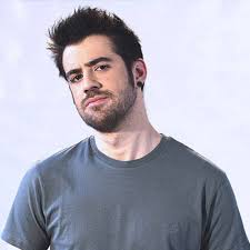 AuronPlay, famoso creador de contenido español, con barba y cabello oscuro, vistiendo una remera gris y mirando de frente con gesto serio.
